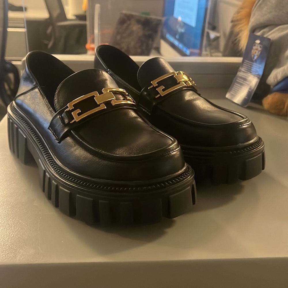 Vegan leather platform penny loafers with gold embellishments.